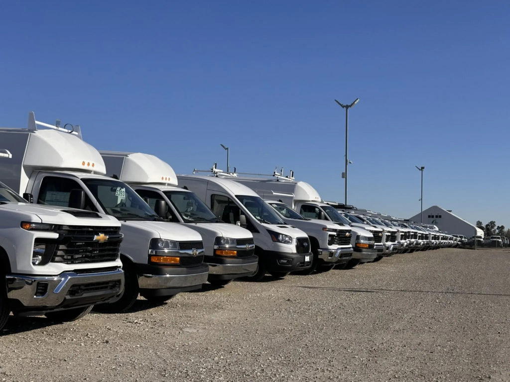 Row of white ADM Auto Services fleet trucks and utility vans parked outdoors